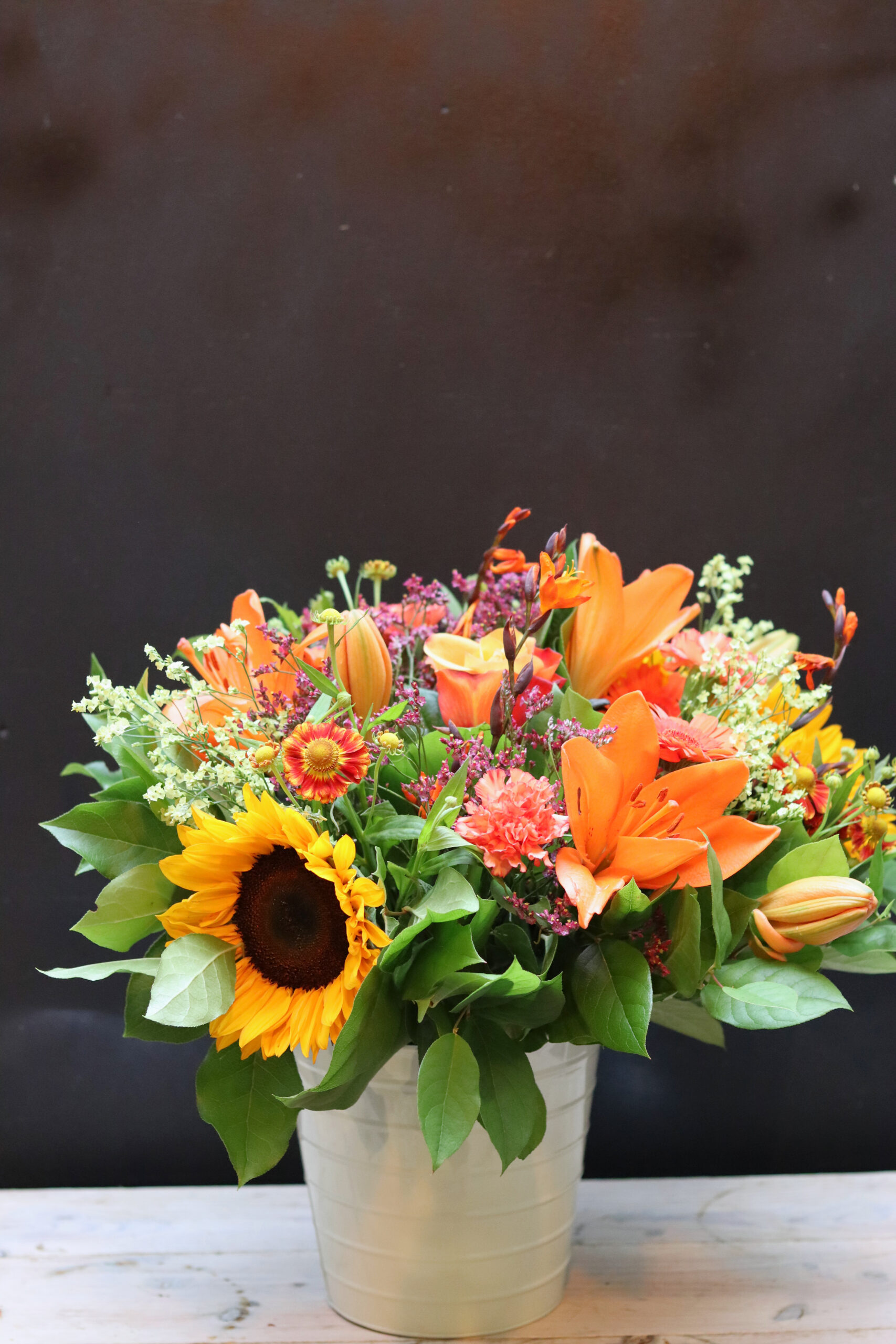 Compleet Zonnegloed boeket met zonnebloem en oranje lelies in crèmekleurige vaas