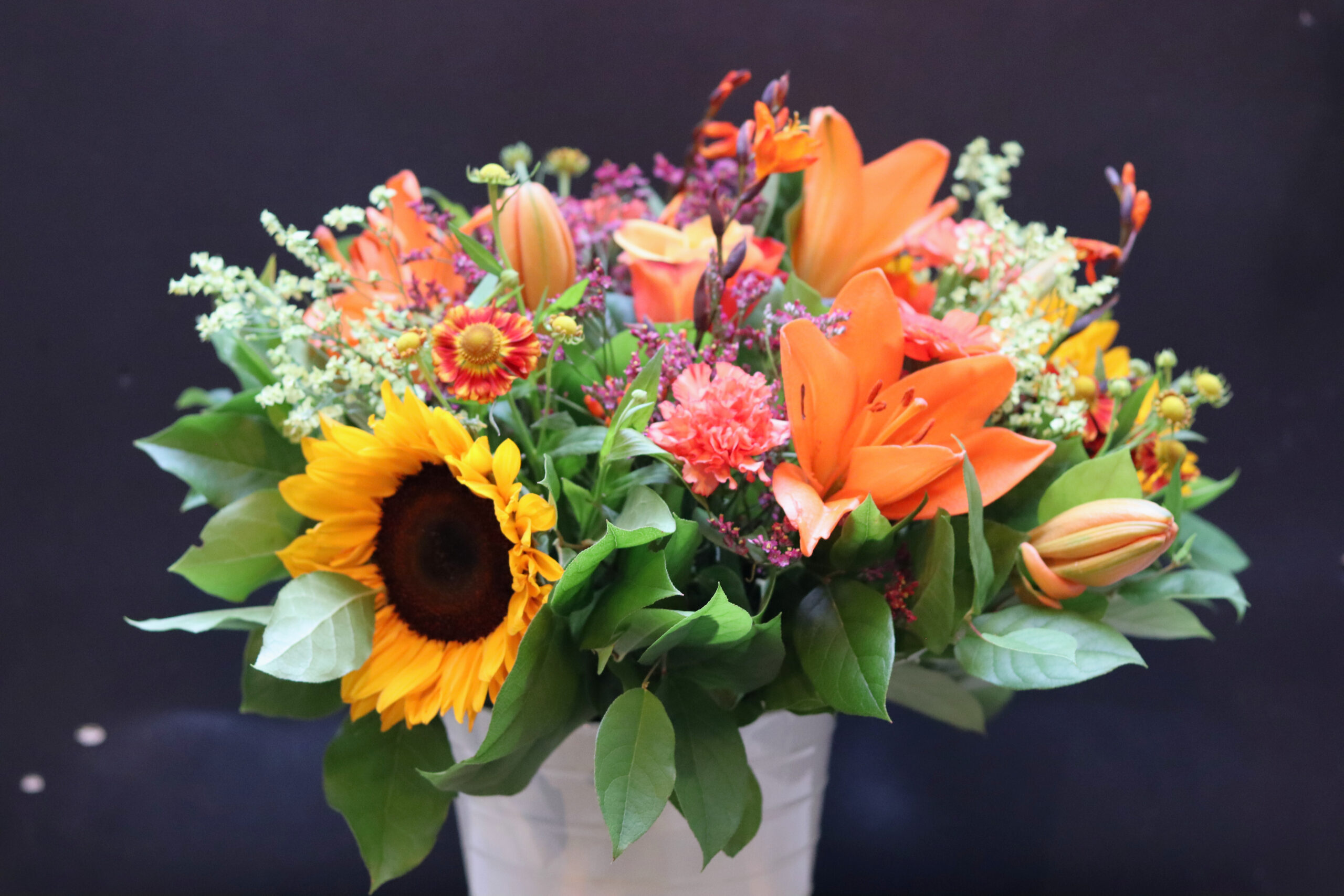 Zonnegloed boeket met gele zonnebloem, oranje lelies en koraalkleurige anjers