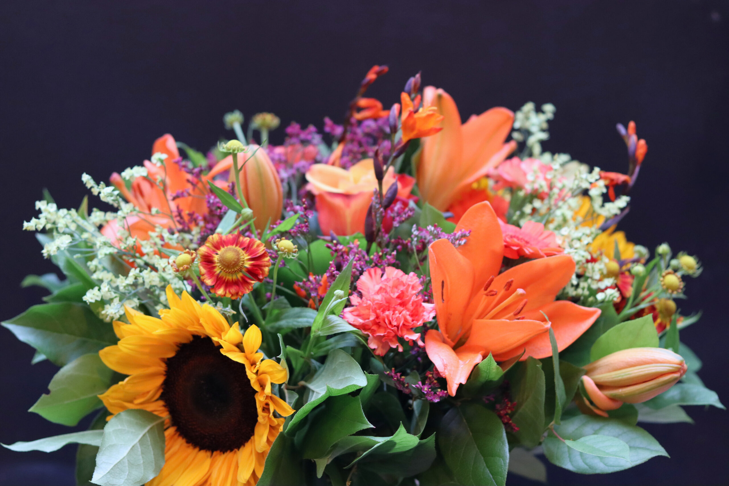 Detailfoto van Zonnegloed boeket met oranje lelie, zonnebloem en anjer
