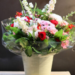 Compleet rood-roze bloemenboeket met witte bloemen in crèmekleurige emmer