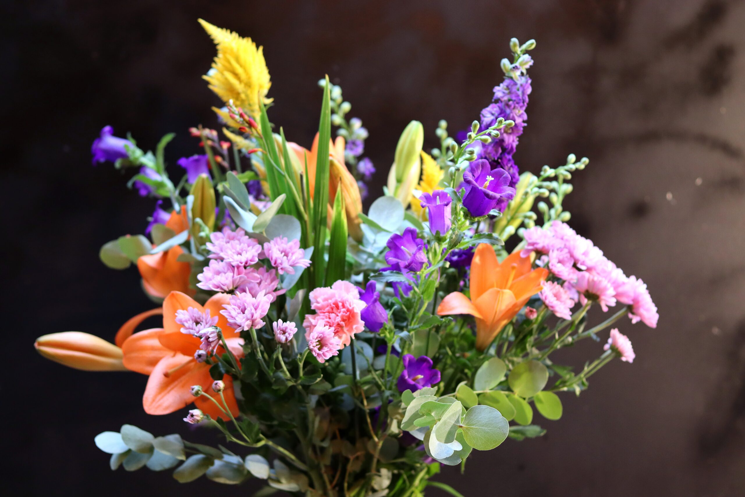 Close-up bovenaanzicht van het Zomerpalet Boeket met oranje lelies, paarse klokjesbloemen en roze chrysanten